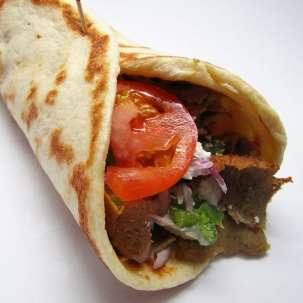 A Pita Place gyro with meat, tomato, red onion, and tzatziki sauce in a pita.