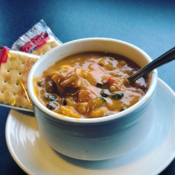 Hearty Greek soup with vegetables and beans in a white bowl, served with crackers.